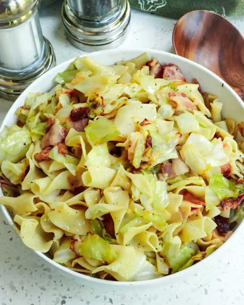 Cabbage, noodles, and bacon in a serving bowl. 