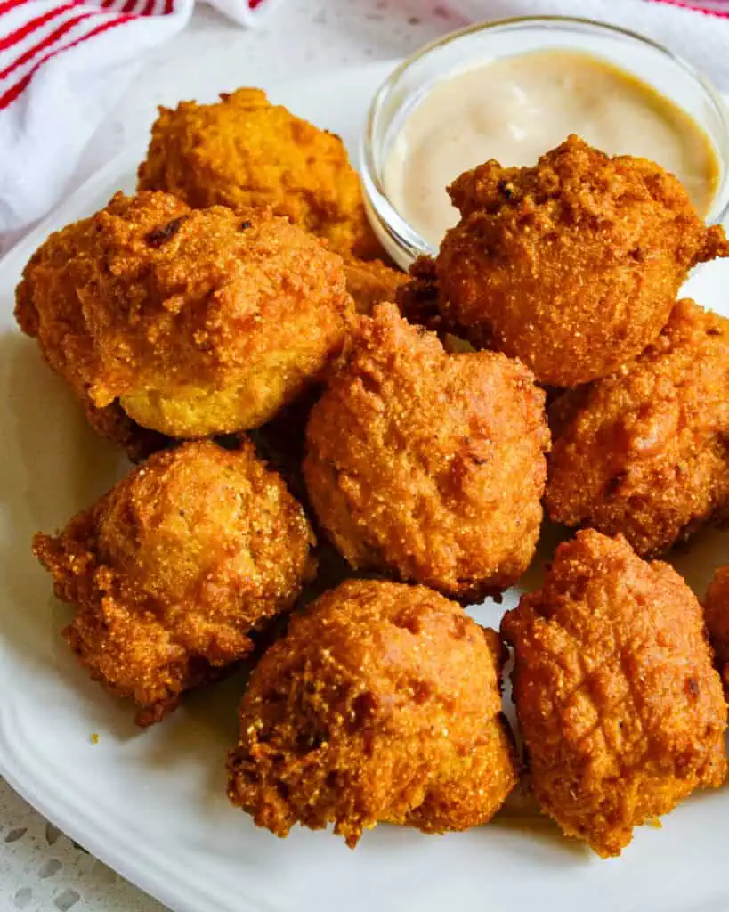 Fried hush puppies on a plate with comeback sauce. 