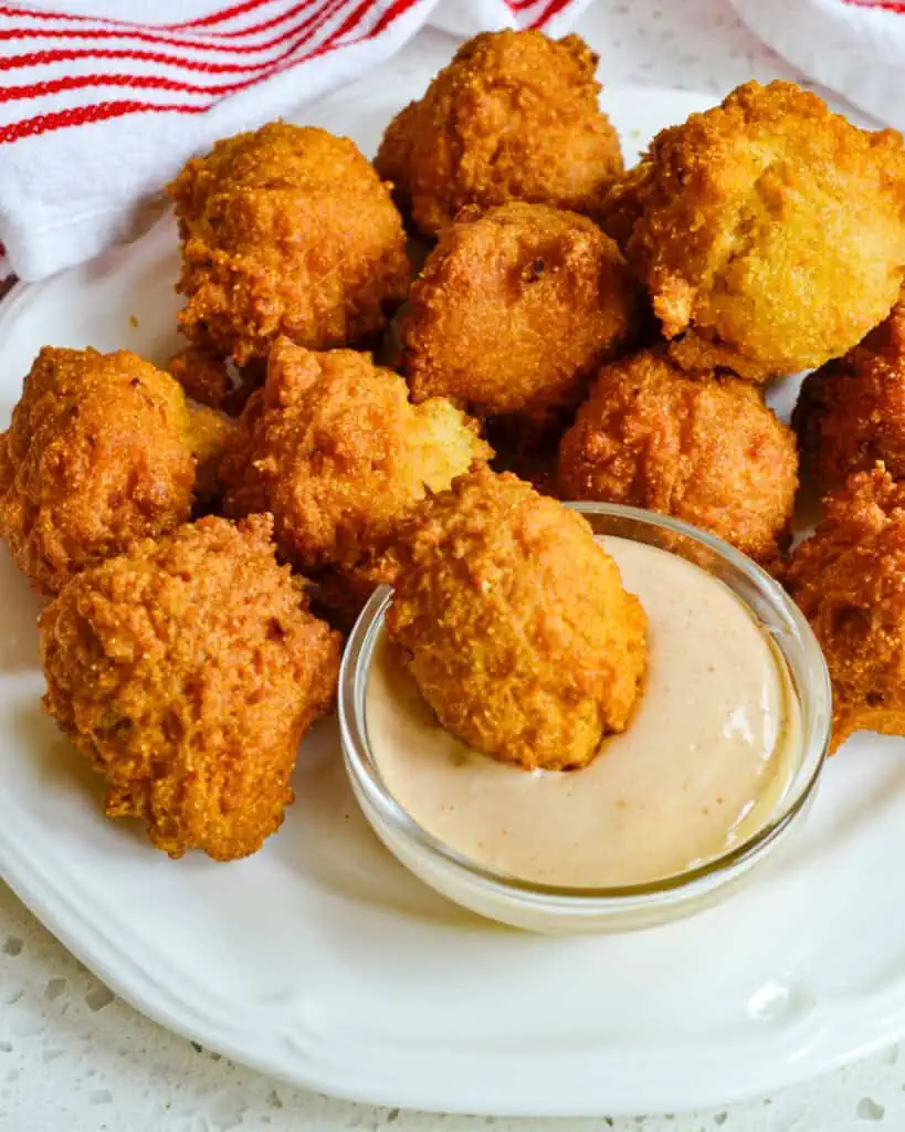 Warm and crispy fried hush puppies with a spicy southern sauce