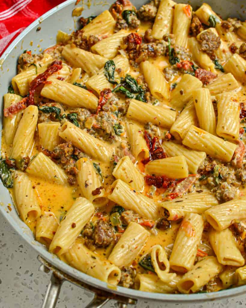 A skillet full of creamy Italian Sausage Pasta with sundried tomatoes and spinach. 