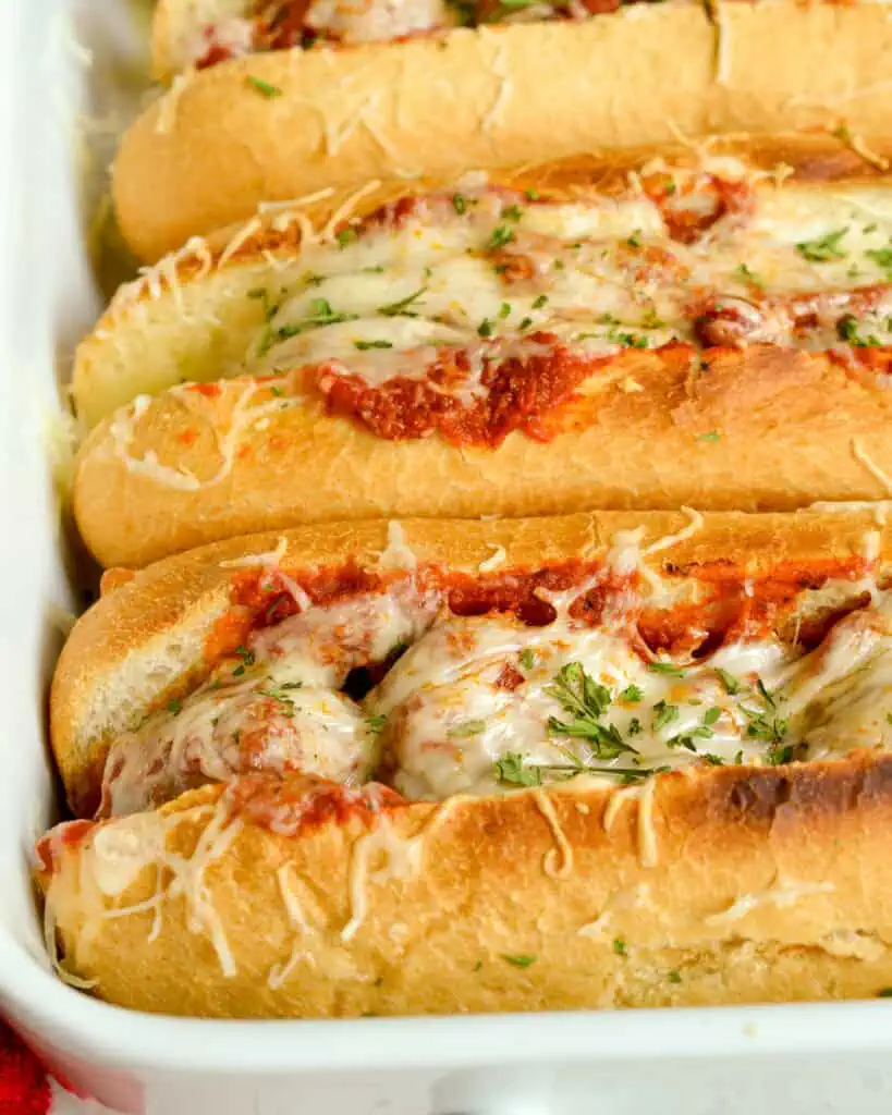 Close up view of meatball subs in a casserole dish. 