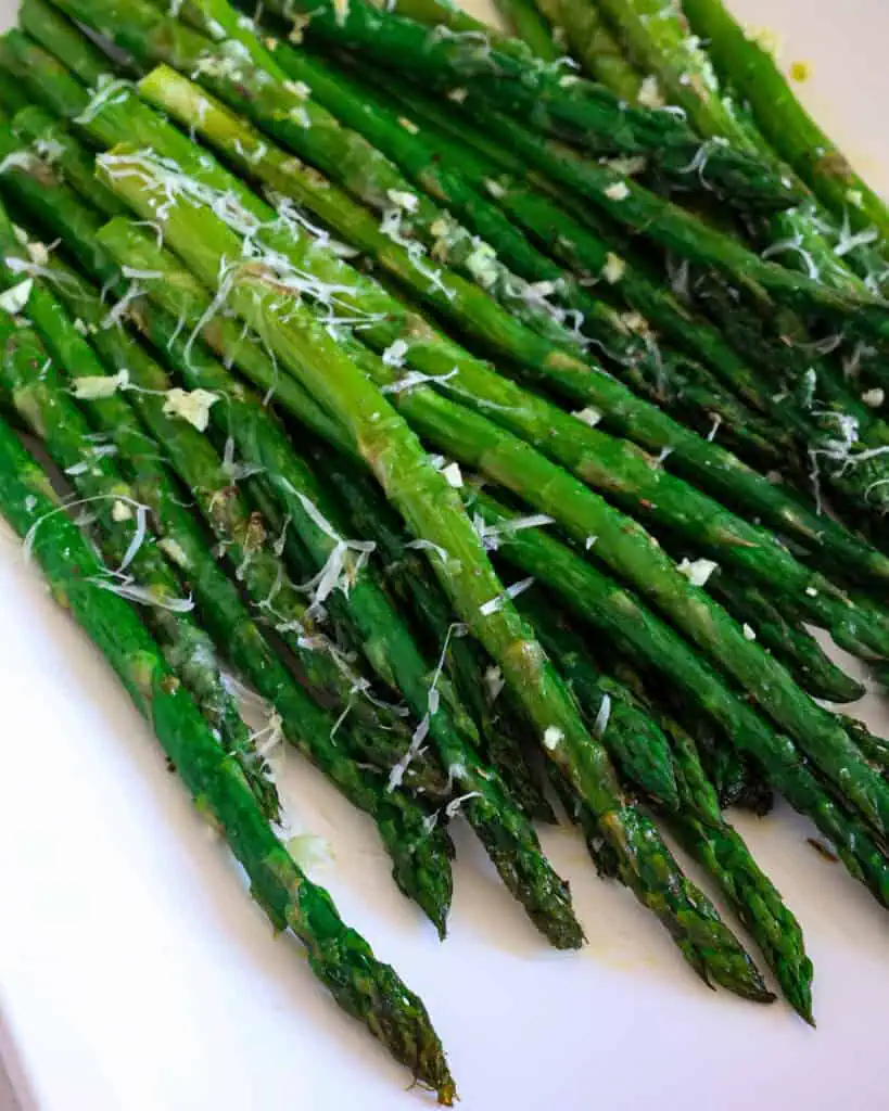 A close up view oven roasted asparagus with garlic and Parmesan cheese. 