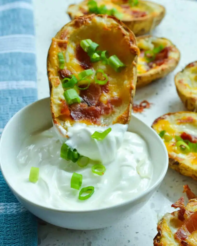 Baked potato skin dipped in a bowl of sour cream. 