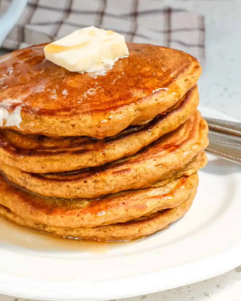 A stack of pumpkin panackes with a pat of butter on the top. 