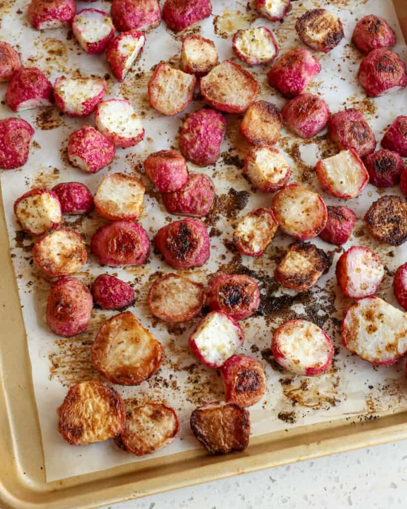 Roasted radishes on a parchment covered baking sheet
