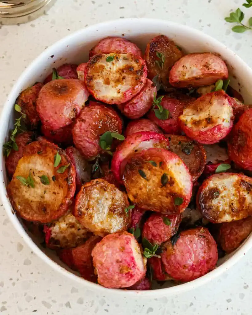 Roasted radishes sprinkled with fresh herbs in a bowl. 