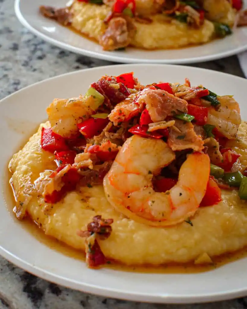 Shrimp and grits with bacon and bell peppers on a plate. 