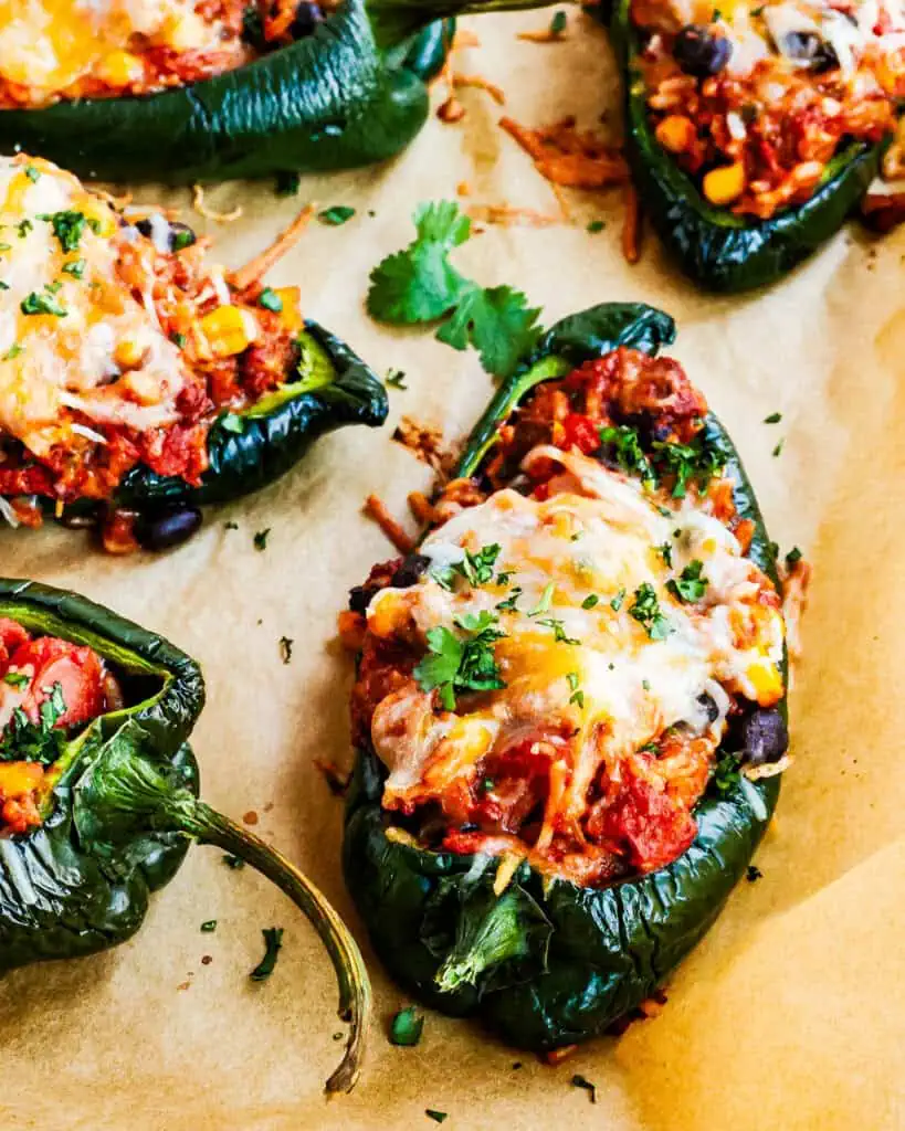 A close up view of stuffed poblano peppers with ground beef, onion, garlic, white rice, corn, black beans, fire-roasted tomatoes, and melty Monterey Jack and cheddar cheese.