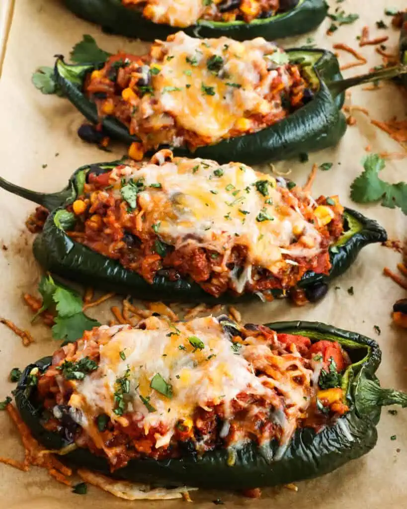 Cheesy stuffed poblano peppers on a parchment covered baking sheet. 