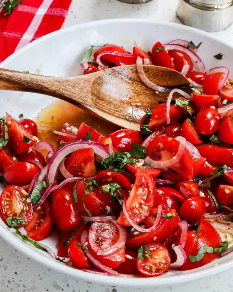 A big bowl of tomato salad with onions, garlic, and fresh basil. 