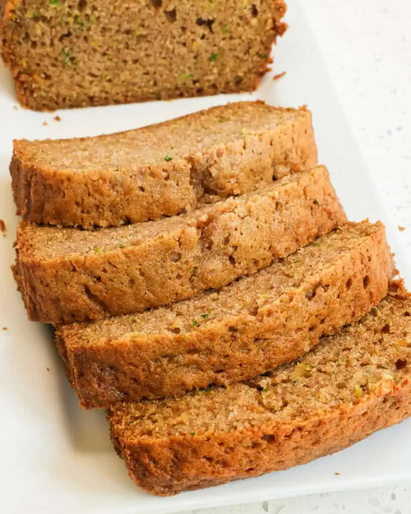 A cut loaf of zucchini bread on a serving platter. 