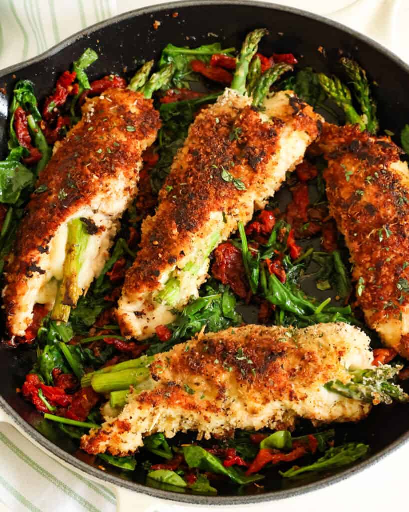 Four asparagus stuffed chicken breasts in a skillet. 