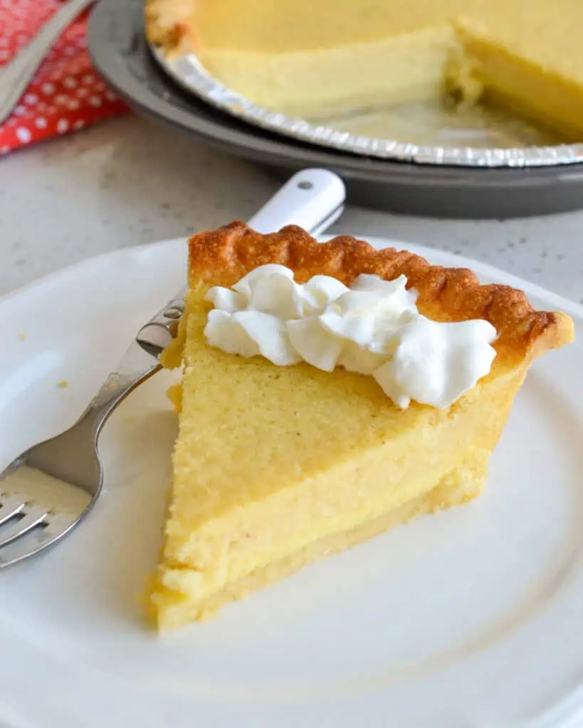 A piece of buttermilk pie with whipped cream on it. 