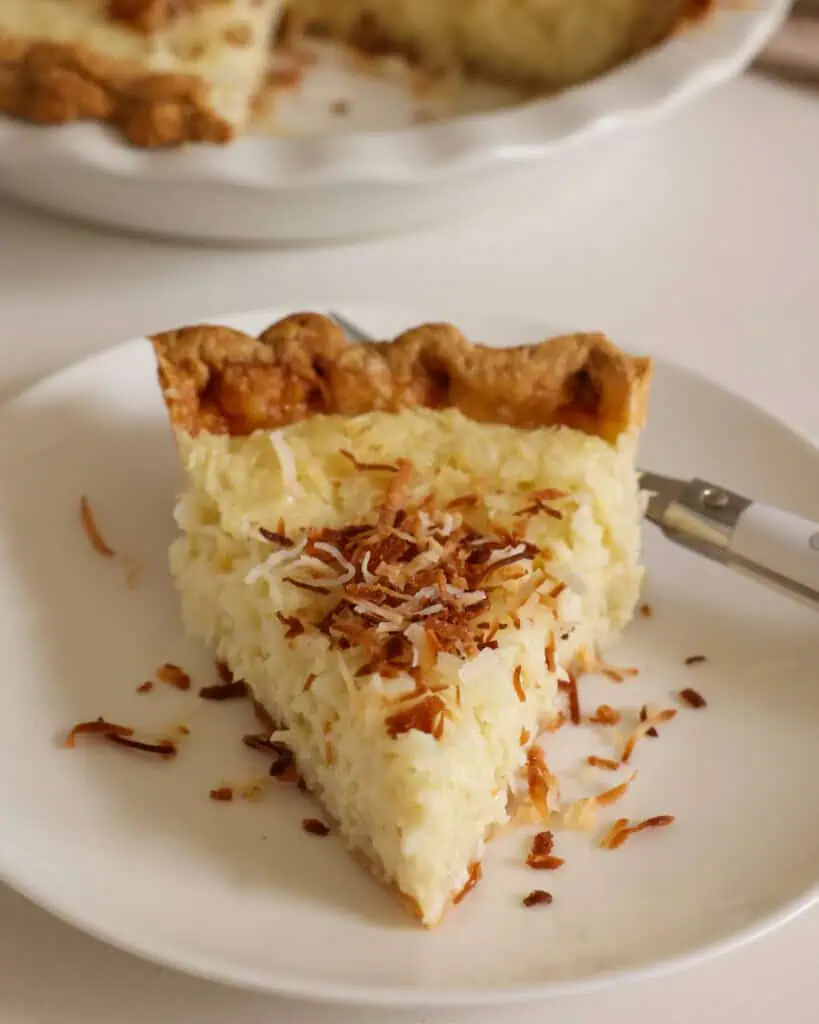 A slice of coconut custard pie on a plate with a fork. 