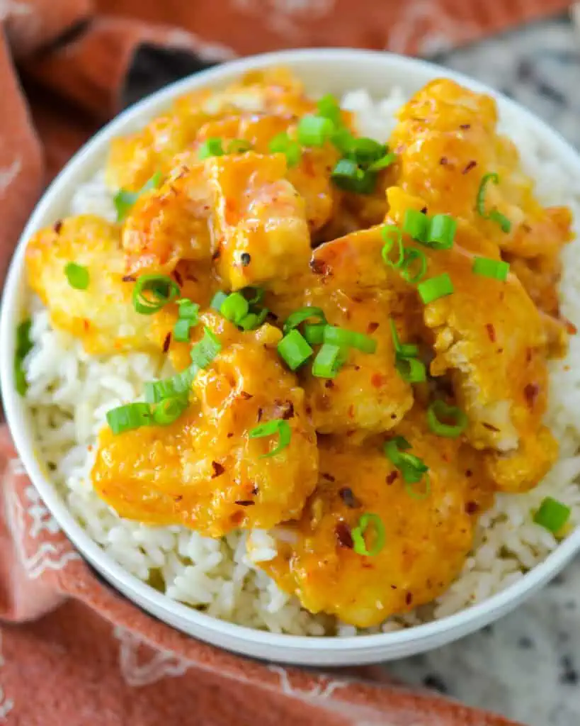 An overview of bang bang shrimp with chopped green onions over rice. 