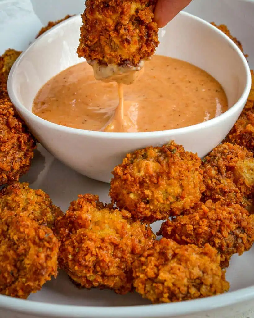 A fried mushroom dipped in a bowl of comeback sauce