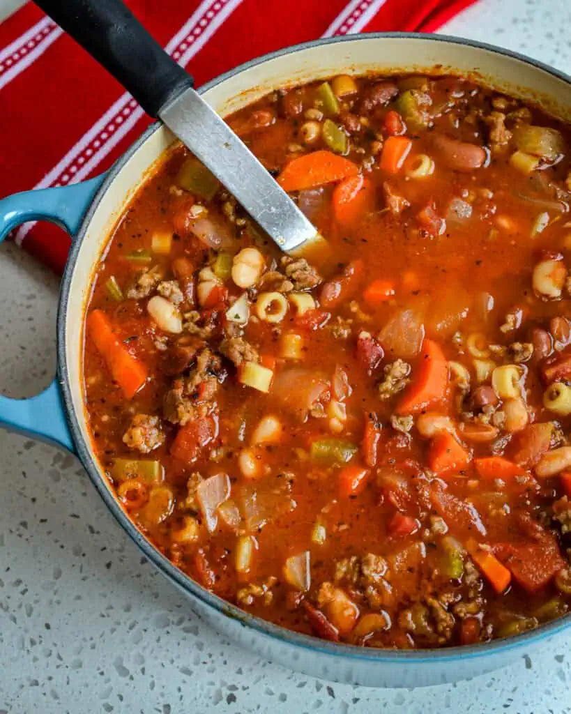 Overhead view of a Dutch oven full of pasta e fagioi with a ladle in it. 