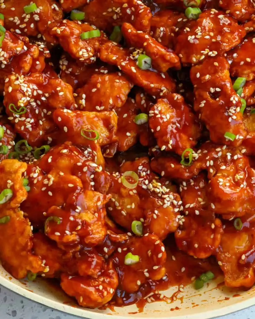 A close up veiw of sesame chicken in a skillet. 