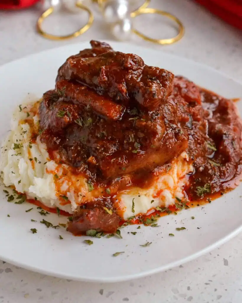 A serving of Swiss steak on a plate with napkins and napkin rings in the background. 