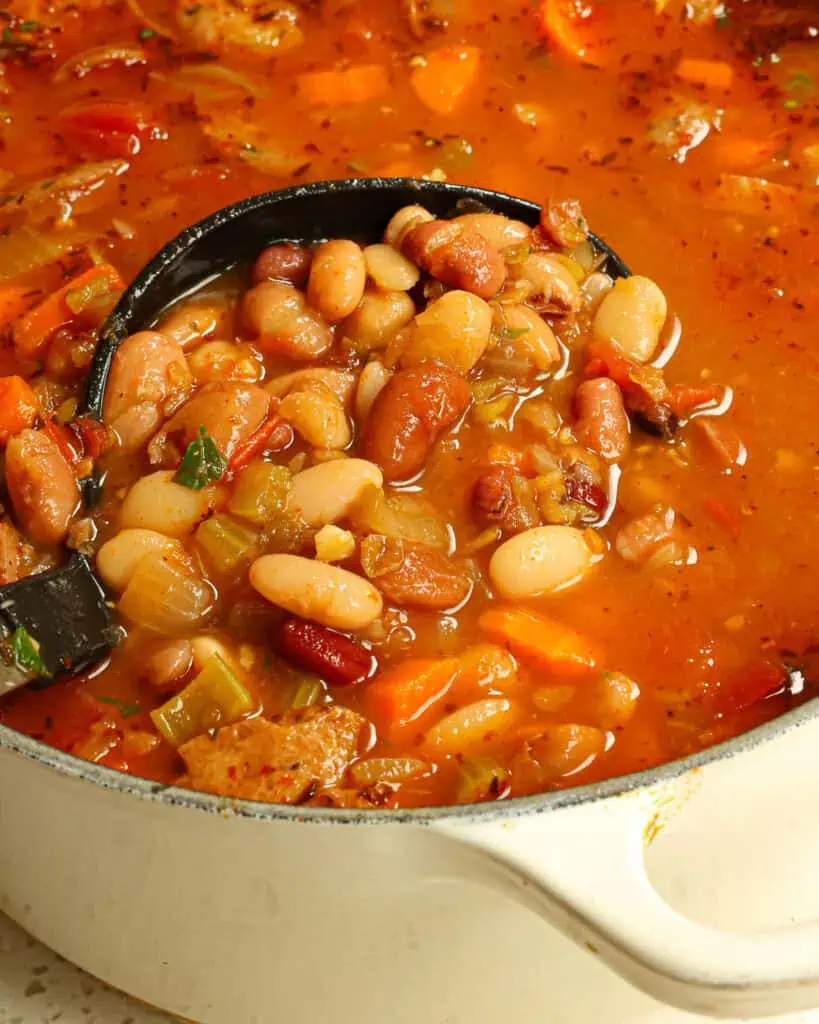 A soup ladle full of 15 bean bean soup in a Dutch oven. 