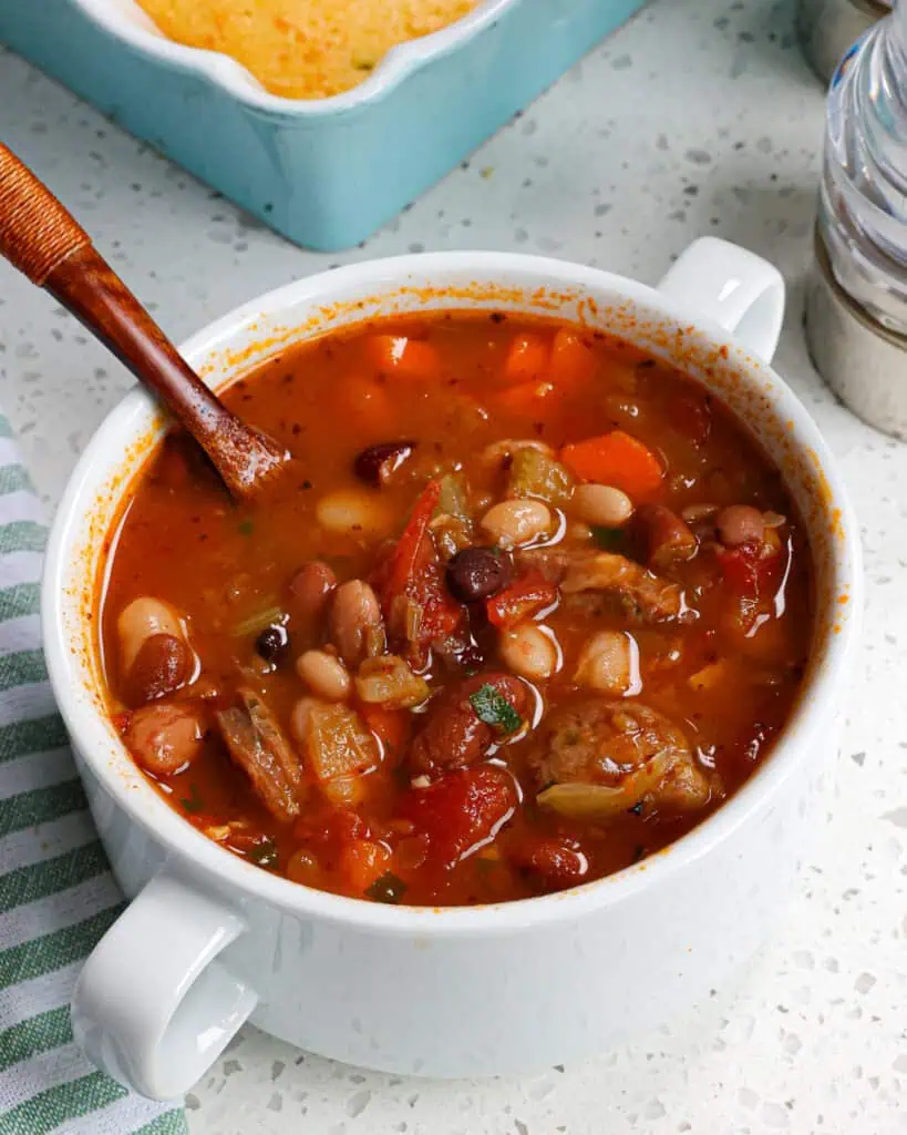 A bowl full of 15-bean soup with cornbread in the background. 