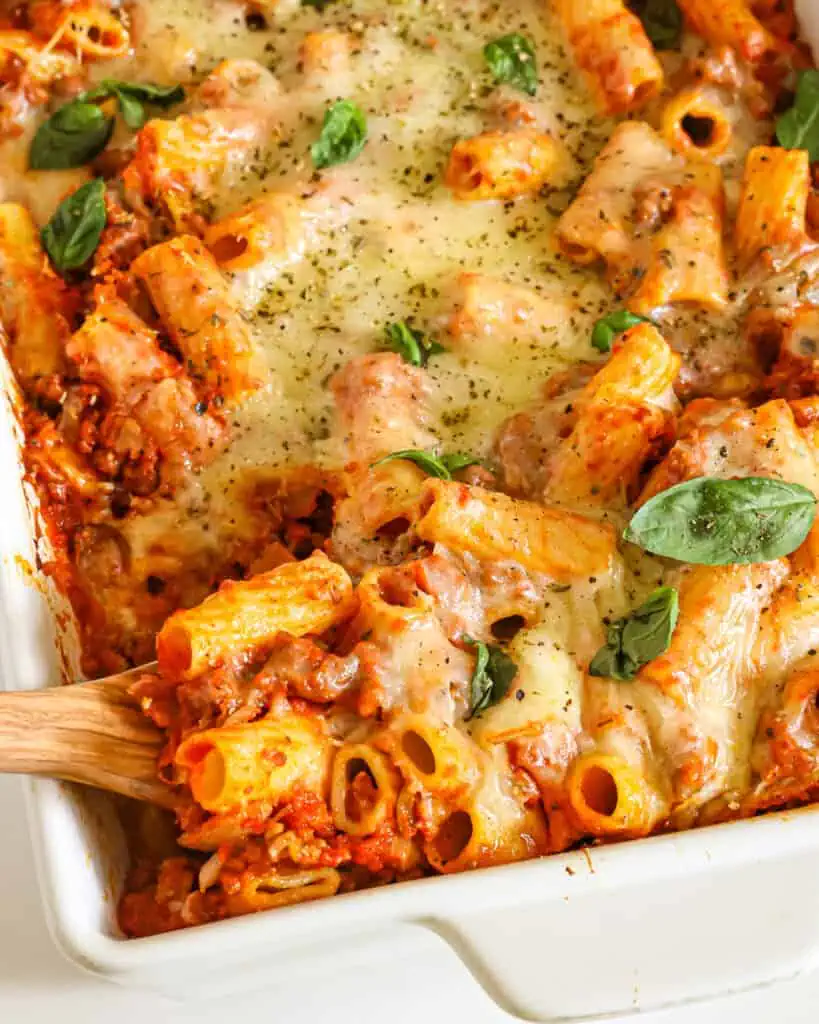 Baked rigatoni with sausage marinara, and melted mozzarella in a large casserole dish 