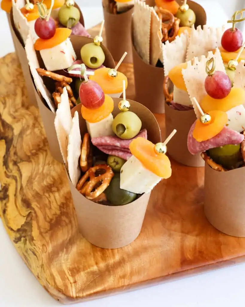 Multiple charcuterie cups on a wooden cutting board. 