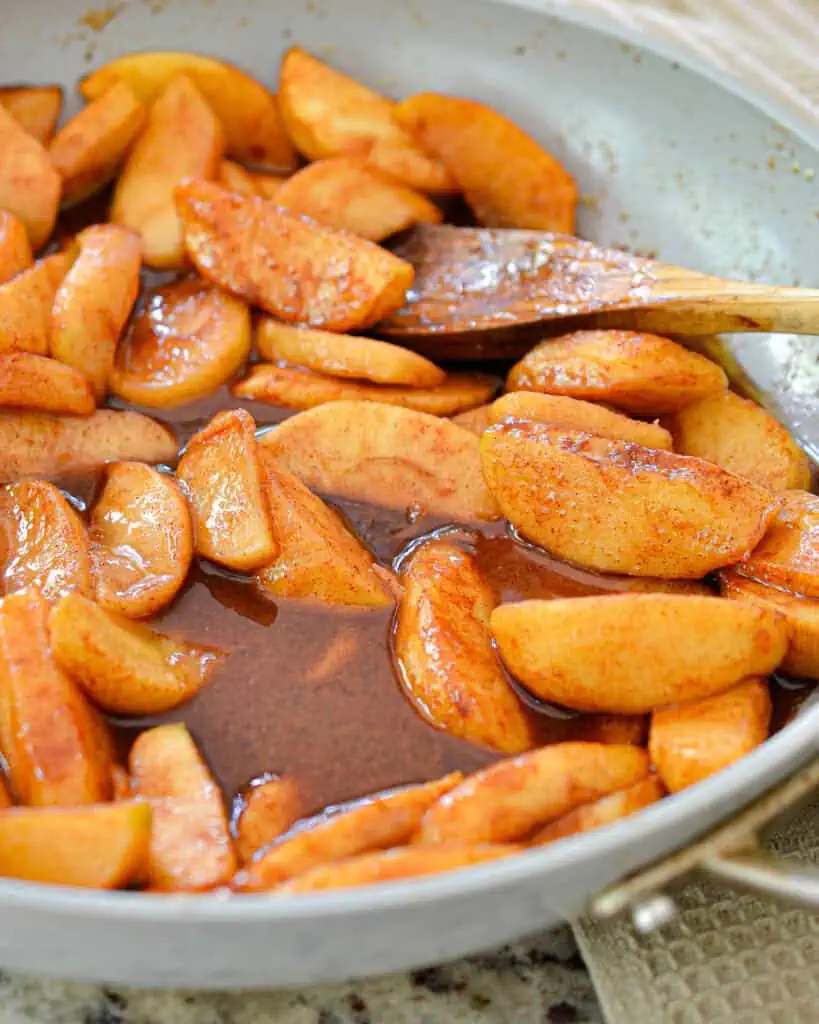 A skillet full of fried apples with cinnamon and nutmeg. 