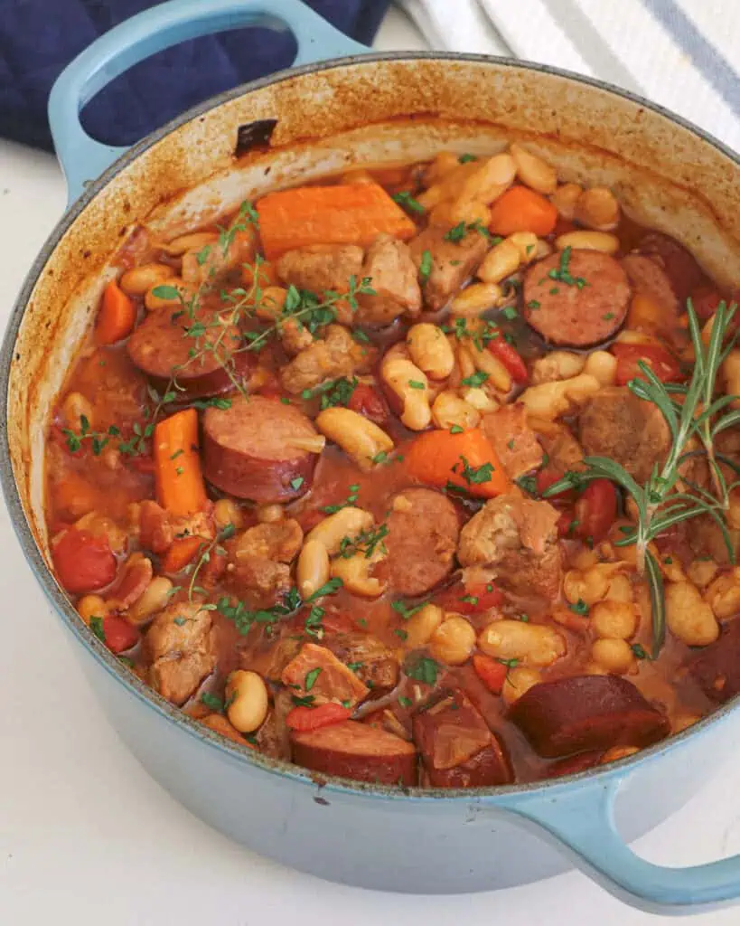 A Dutch oven full of French cassoulet with fresh herbs. 