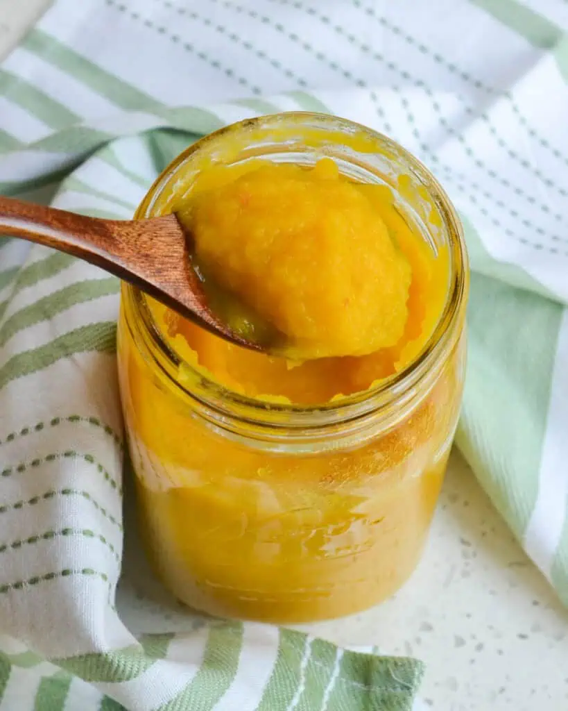 Pumpkin puree in a mason jar with a spoon full of pumpkin puree. 