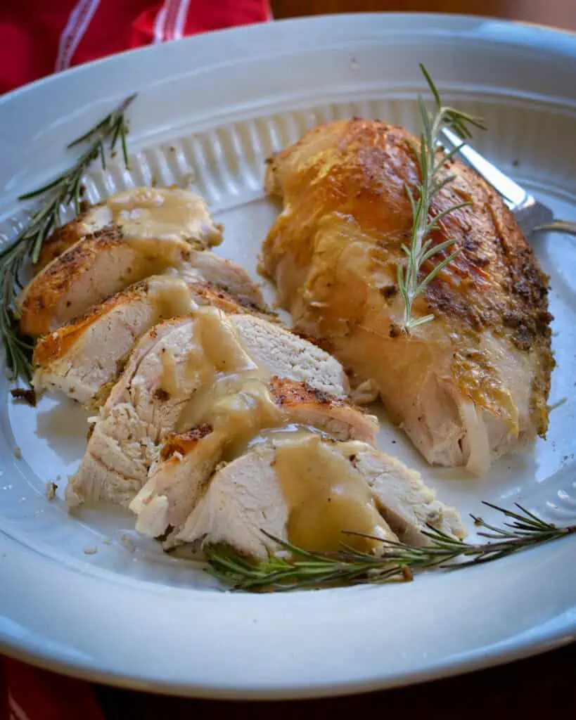 Sliced turkey breast drizzled with gravy on platter. 