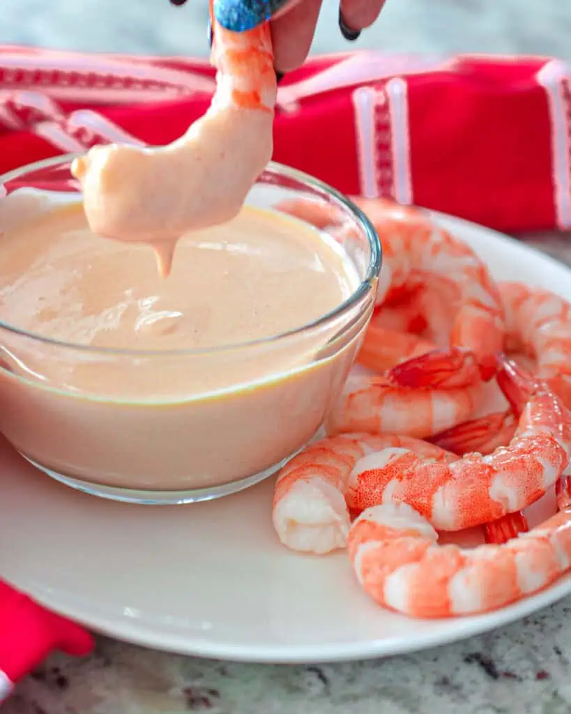 Yum yum sauce in a small bowl with cooked shrimp dipped in it. 