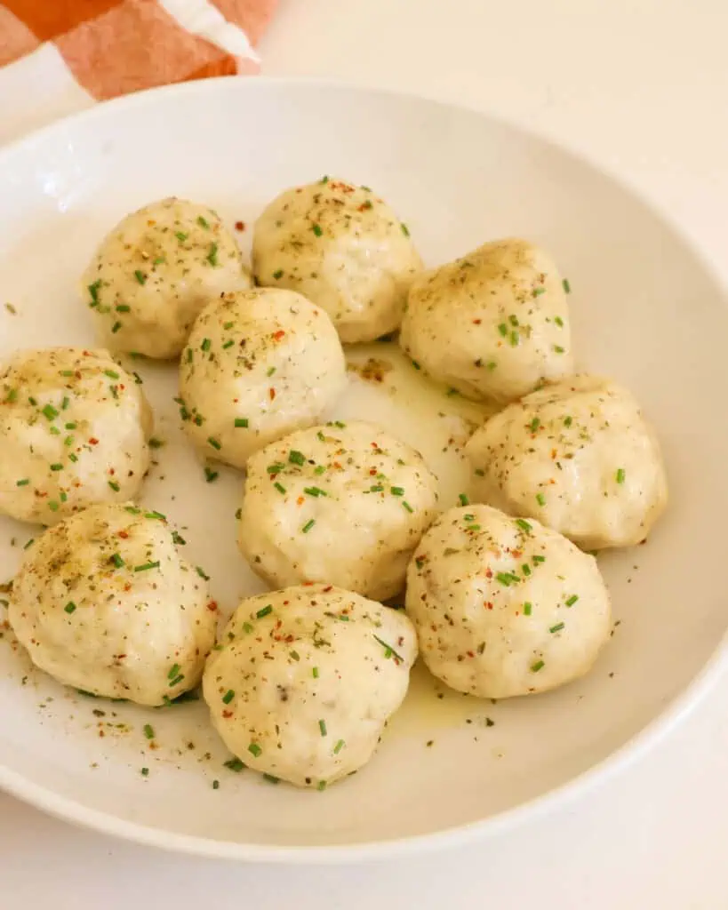 Potato dumplings sprinkled with chopped chives in a serving bowl.