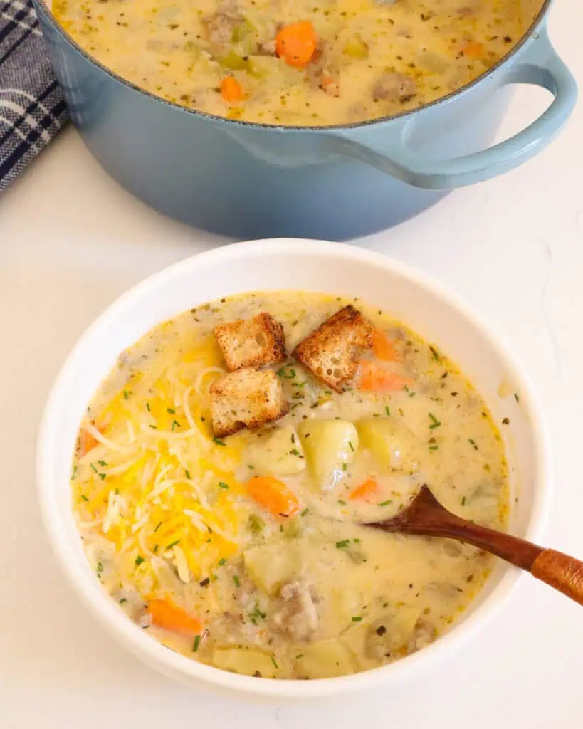 a single serving bowl full of sausage potato soup topped with croutons and cheese. 