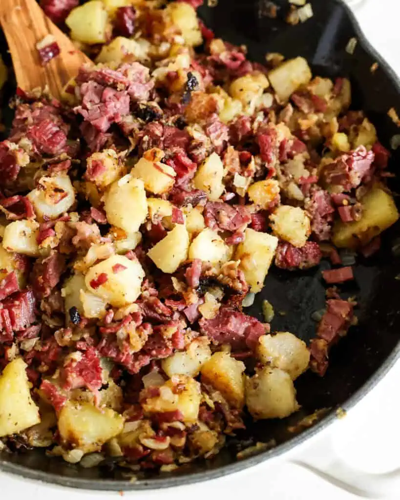 A close up view of corned beef hash in a cast iron skillet. 