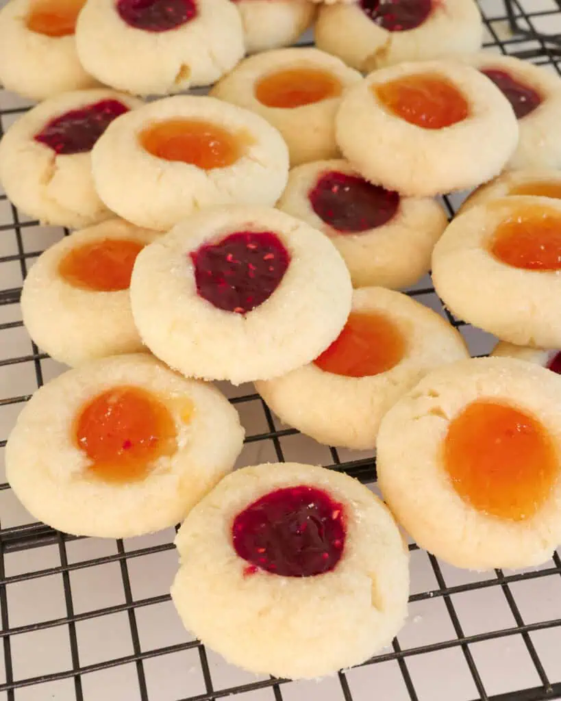 Close up view of raspberry and apricot thumbprint cookies on a cooling rack. 