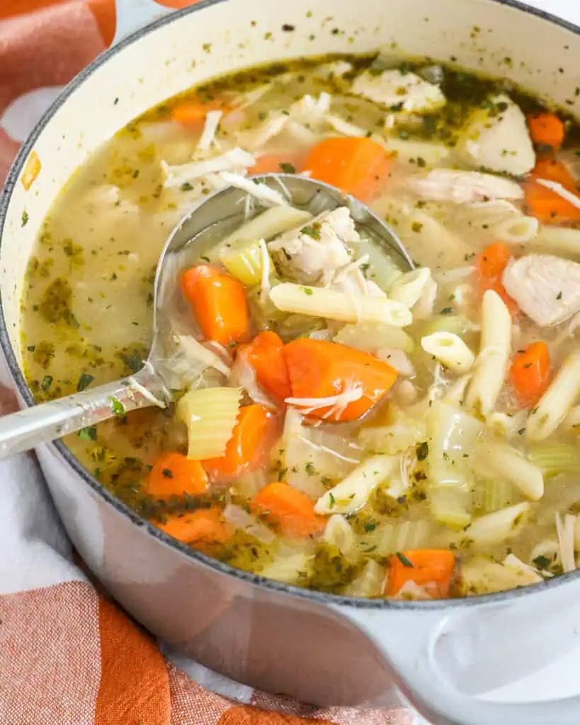 A Dutch oven and ladle full of turkey noodle soup. 