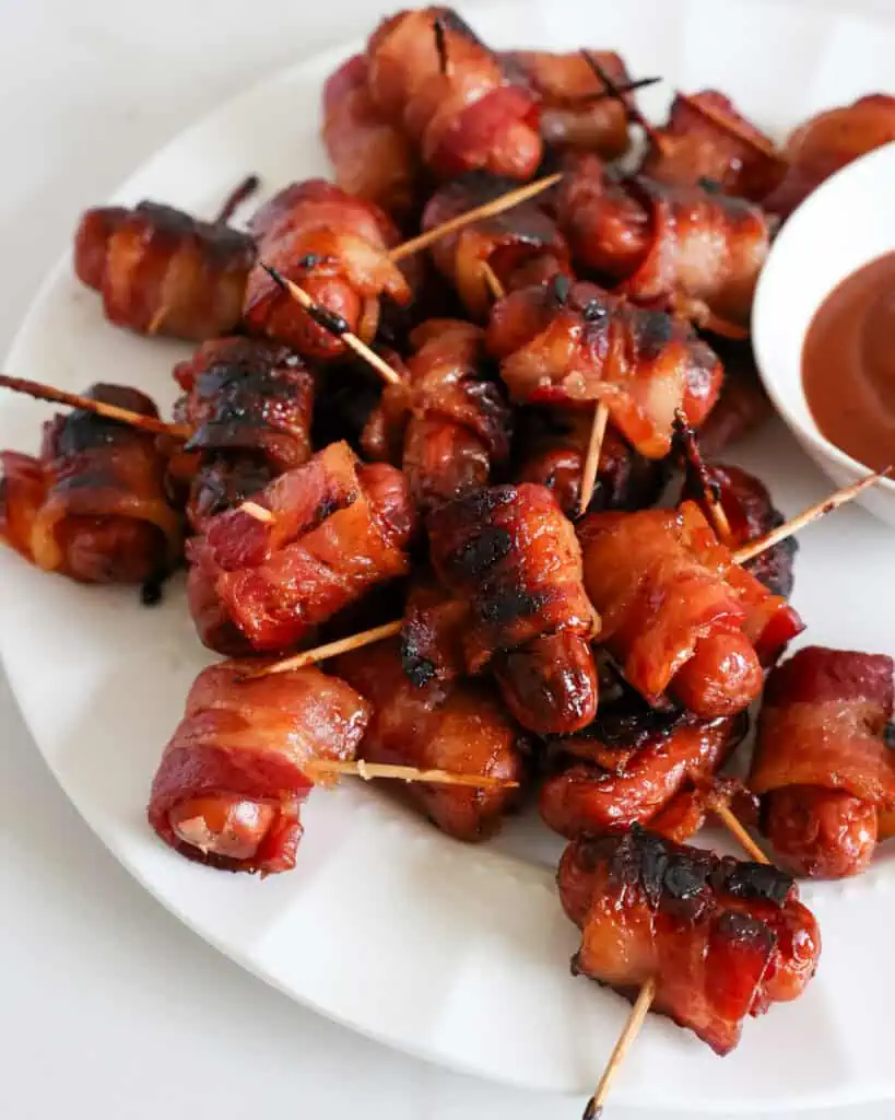 A plate full of smokies wrapped in bacon and basted with brown sugar. 