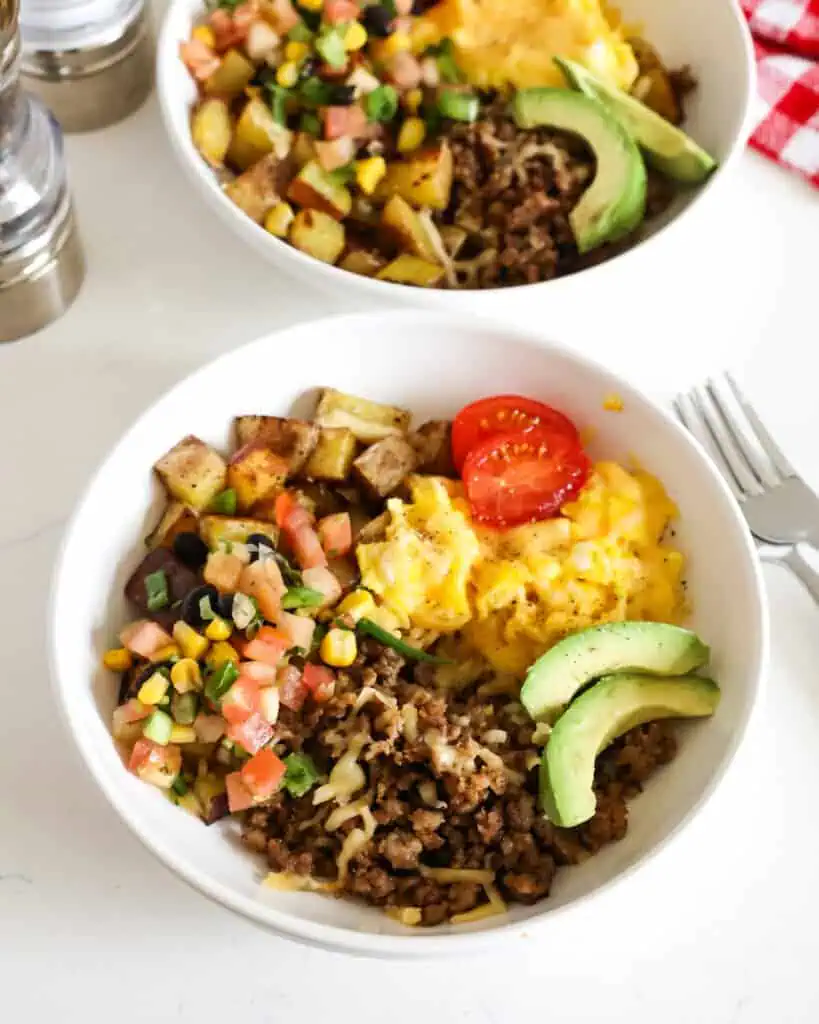 Breakfast bowls topped with grape tomatoes, Pico de Gallo, and sliced avocado. 