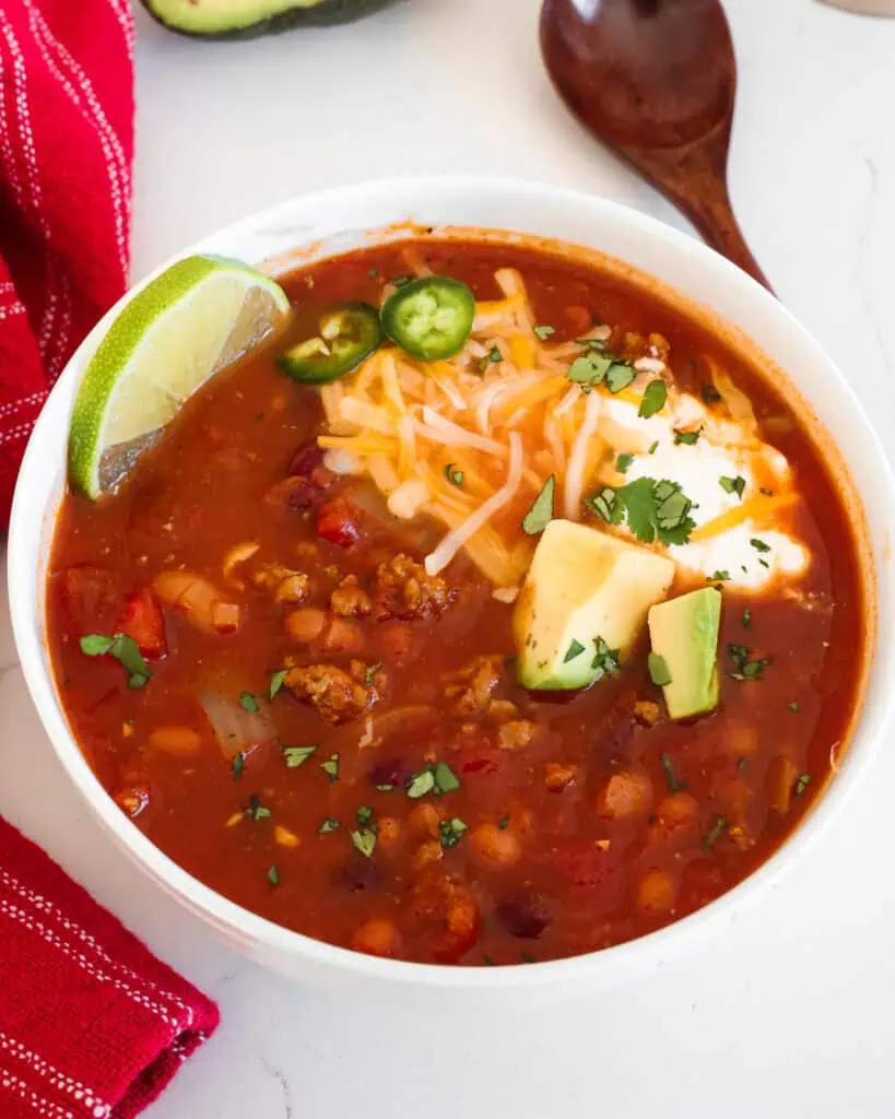 A single bowl of turkey chili with jalapeno rings, shredded cheese, and sour cream. 