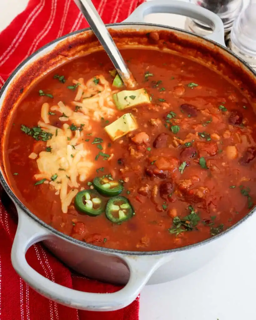 A Dutch oven full of turkey chili with kidney beans, onions, and garlic. 