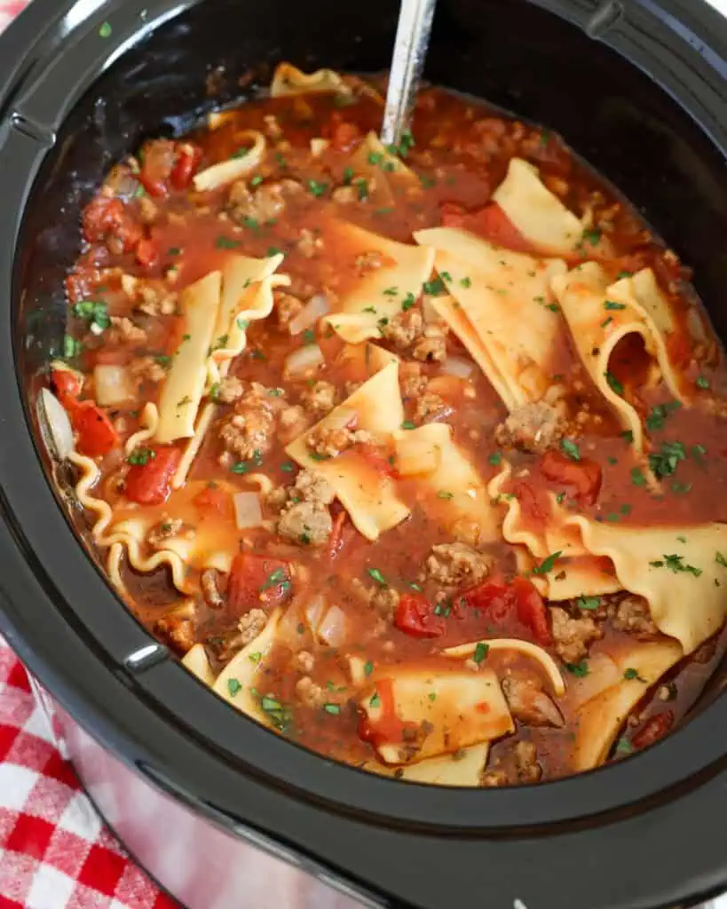 A crockpot full of lasagna soup topped with chopped fresh parsley. 