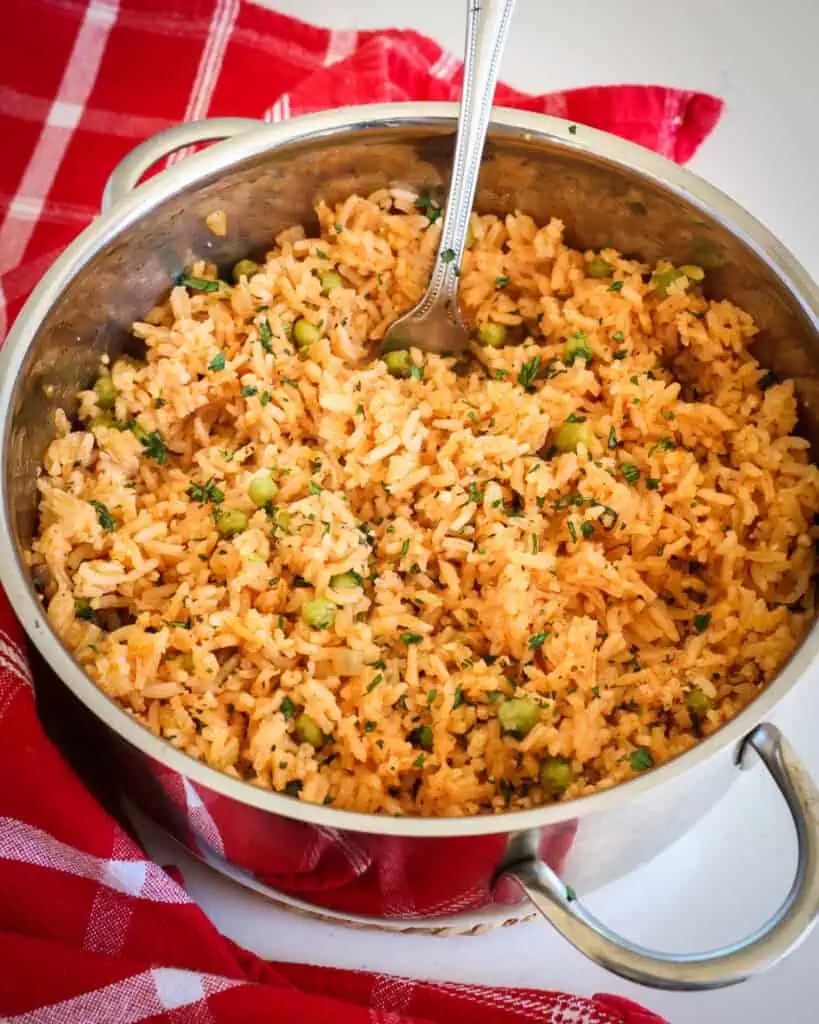 A pot full of Mexican rice with a fork in it to fluff the rice. 