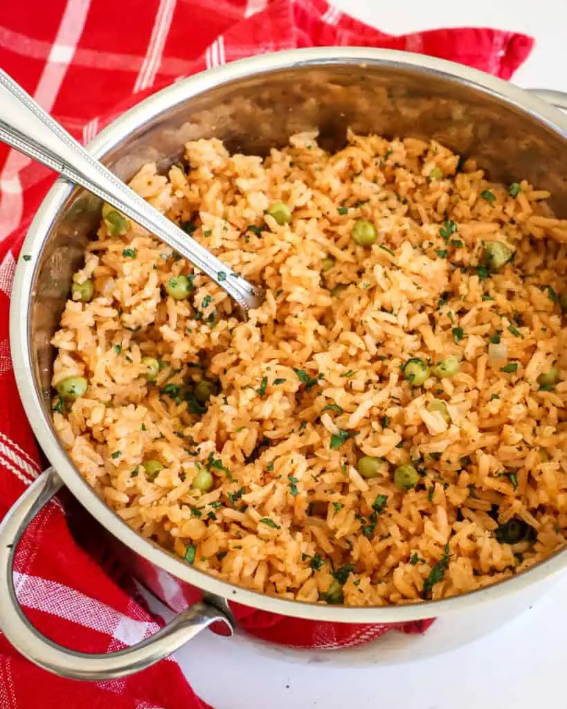 A pot full of Mexican rice with onions, green peas, and cilantro. 